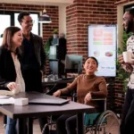 asian-woman-wheelchair-group-people-laughing-job-break-having-fun-disability-friendly-office-worker-with-chronic-health-condition-chatting-with-cheerful-colleagues
